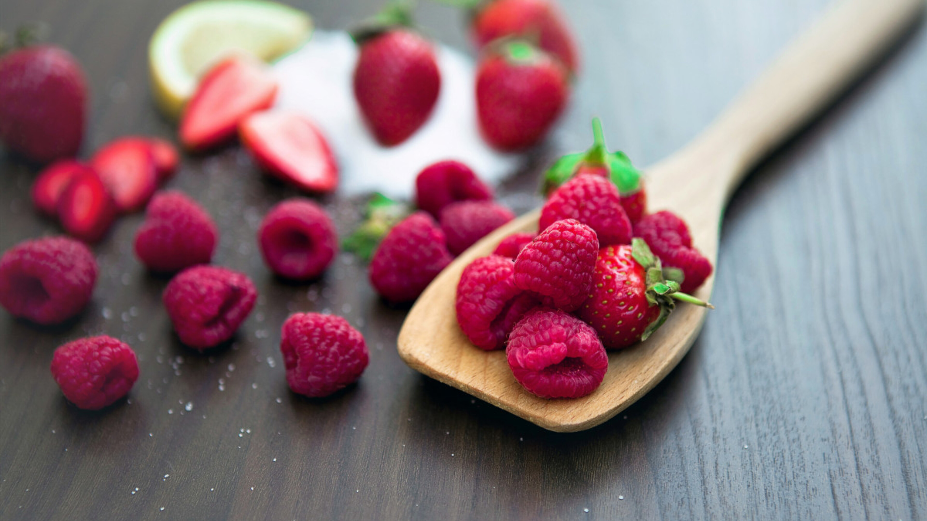 Raspberries on a table with a wooden spoon