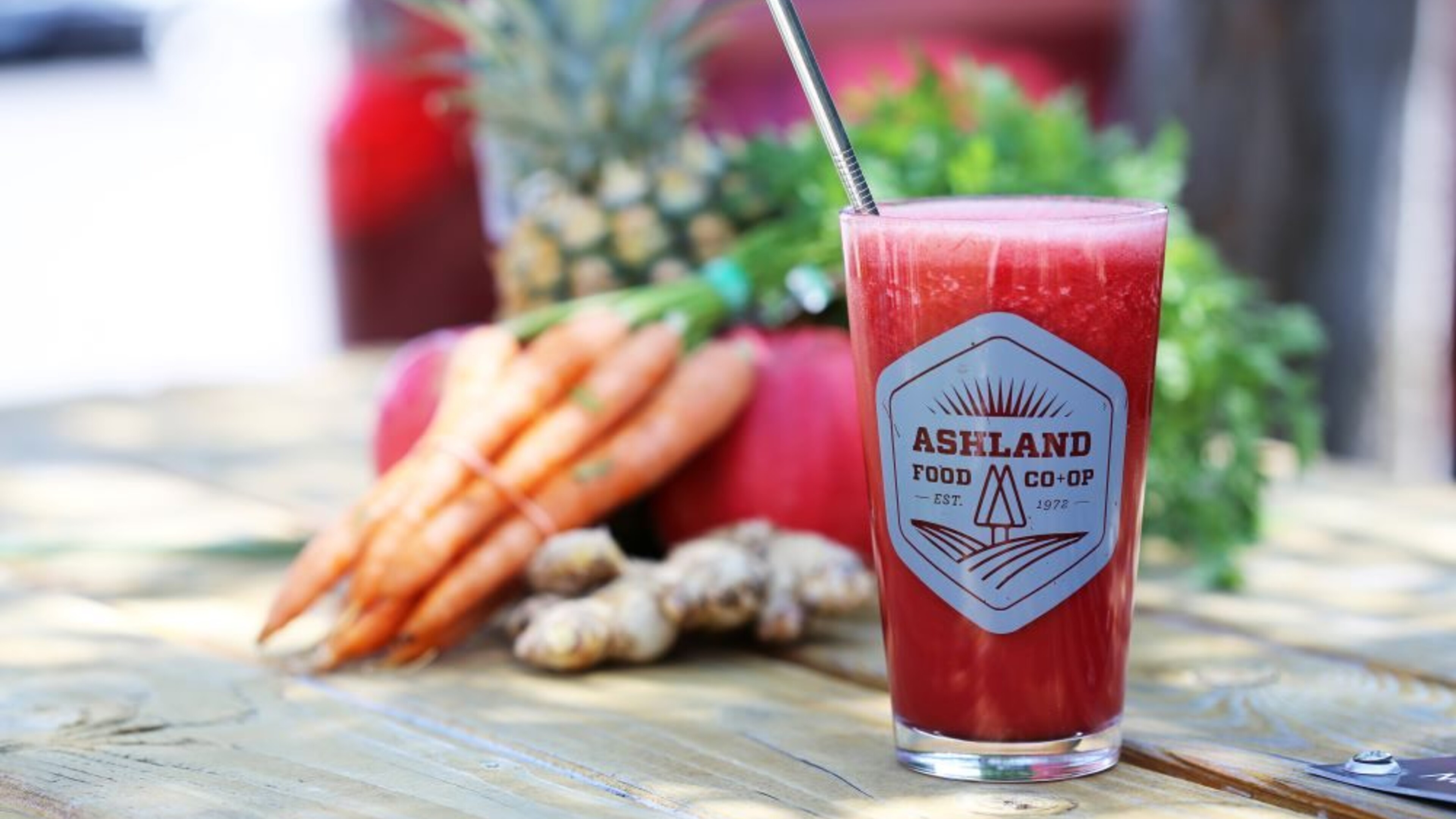 Picnic table with a smoothie in a Co-op pint glass with fresh vegetables in the backgrount