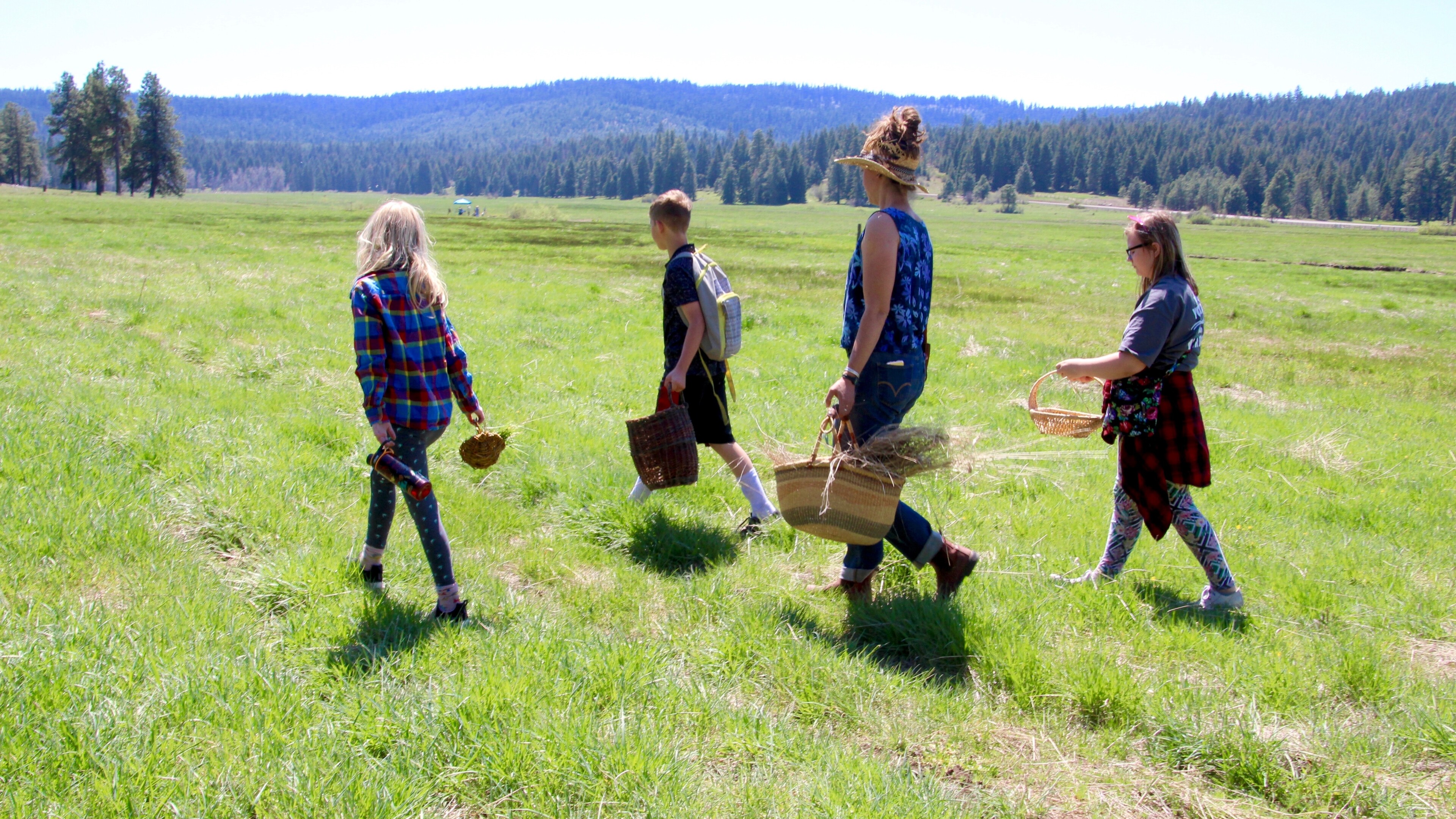 group of people walking across a field carrying baskets