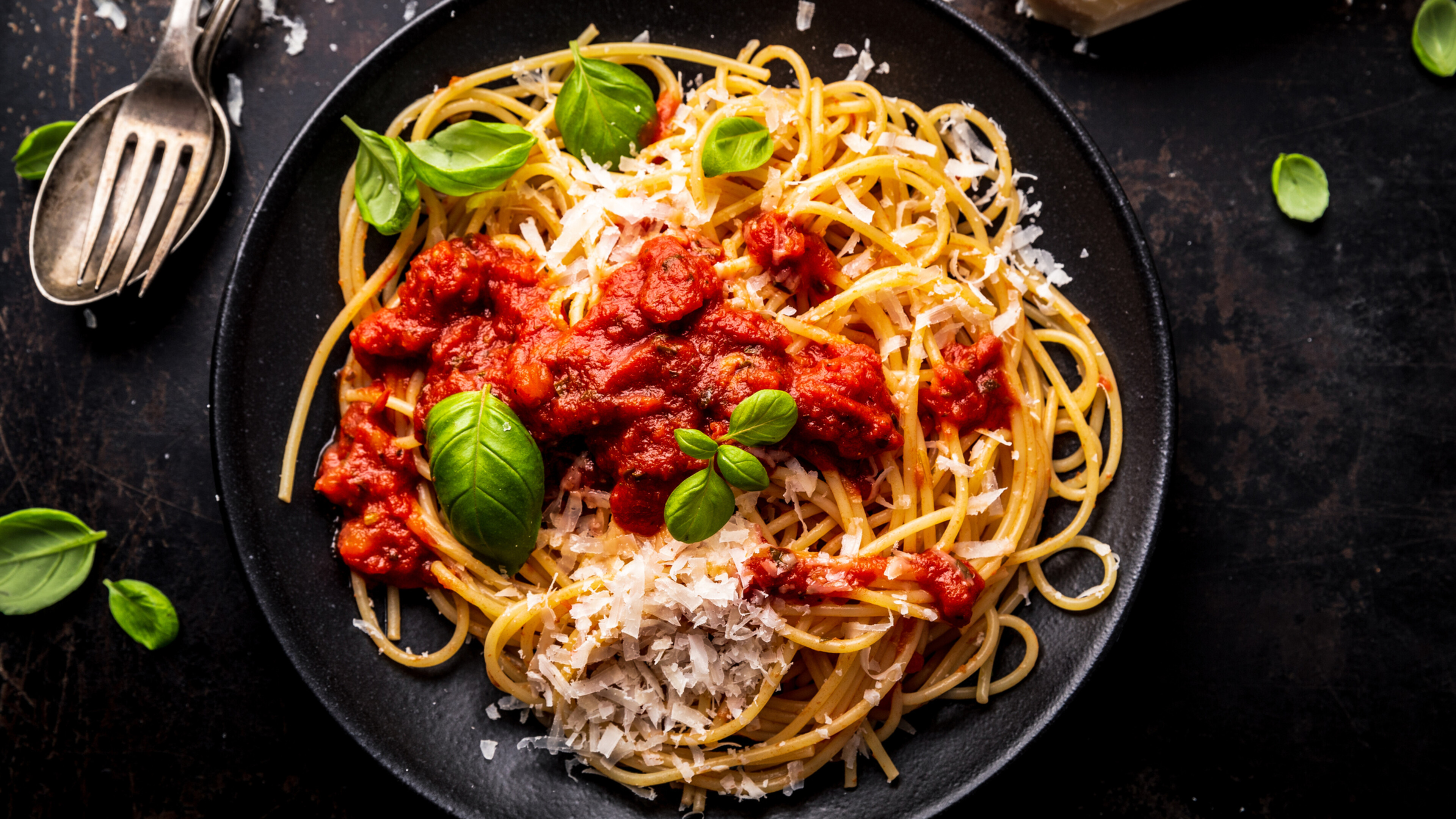 spaghetti with marinara sauce and basil in a black bowl