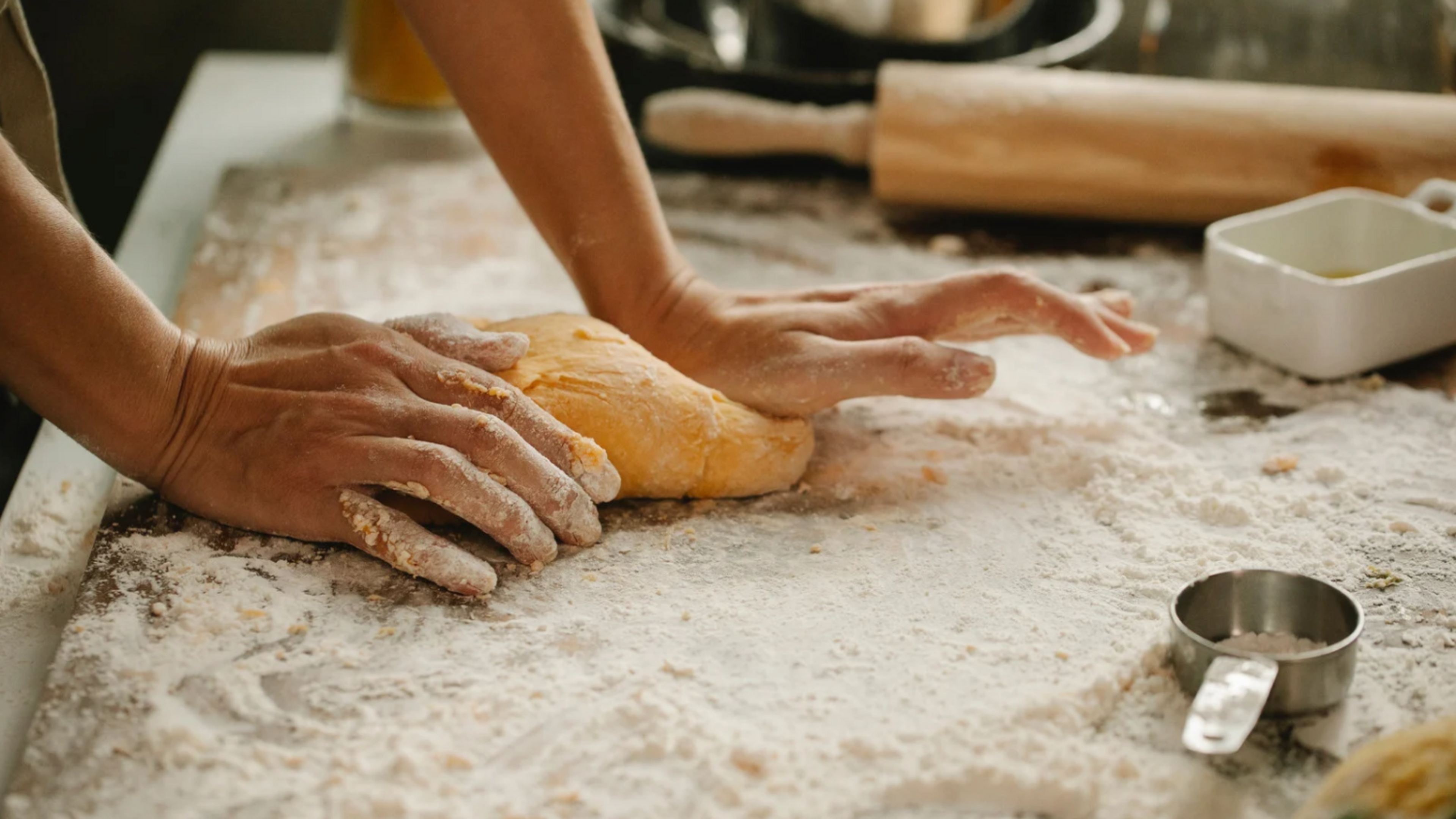 close up of hands rolling out dough