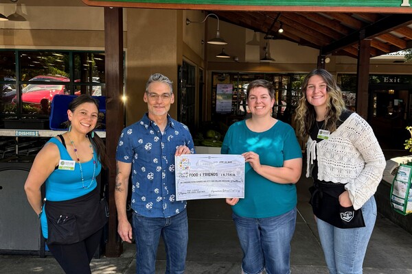 Four people standing in front of Ashland Food Co-op being presented with a check