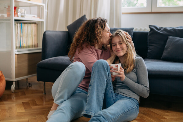 two women sitting on the floor one is kissing the other on the head