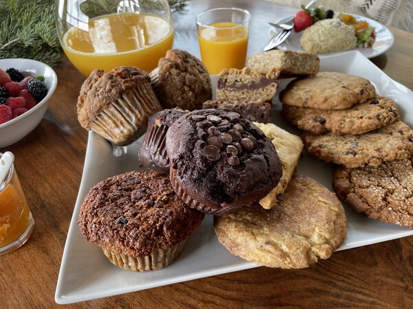 assortment of baked goods on a white plate with glass of orange juice in the background