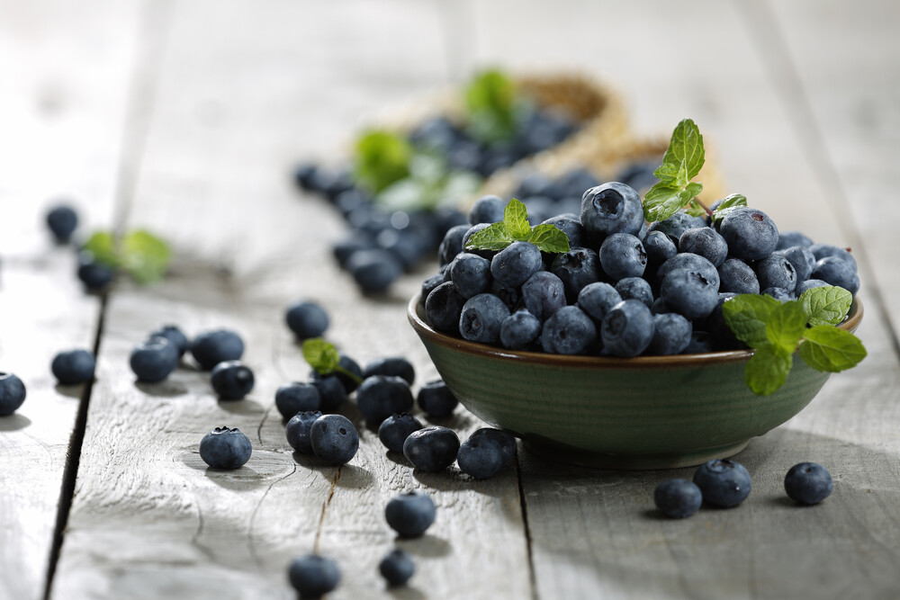 bowls of blueberries with mint leaves on a rustic table