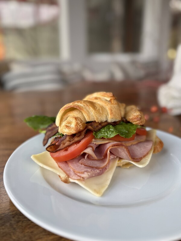 Club sandwich on a croissant on a white plate