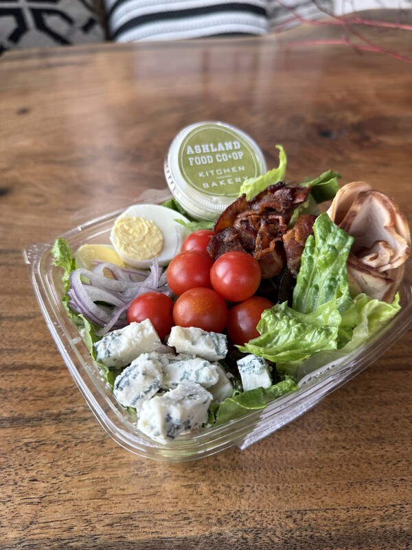 Cobb salad in a to go container on a wooden surface