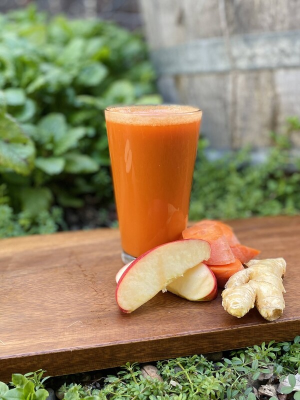 carrot apple ginger smoothie on a wooden cutting board