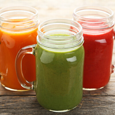orange green and red juices in mason jars with handles