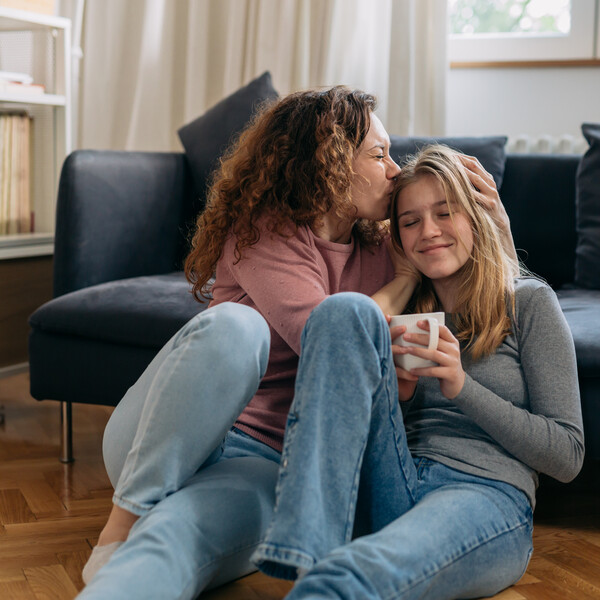 two women sitting on the floor one is kissing the other on the head