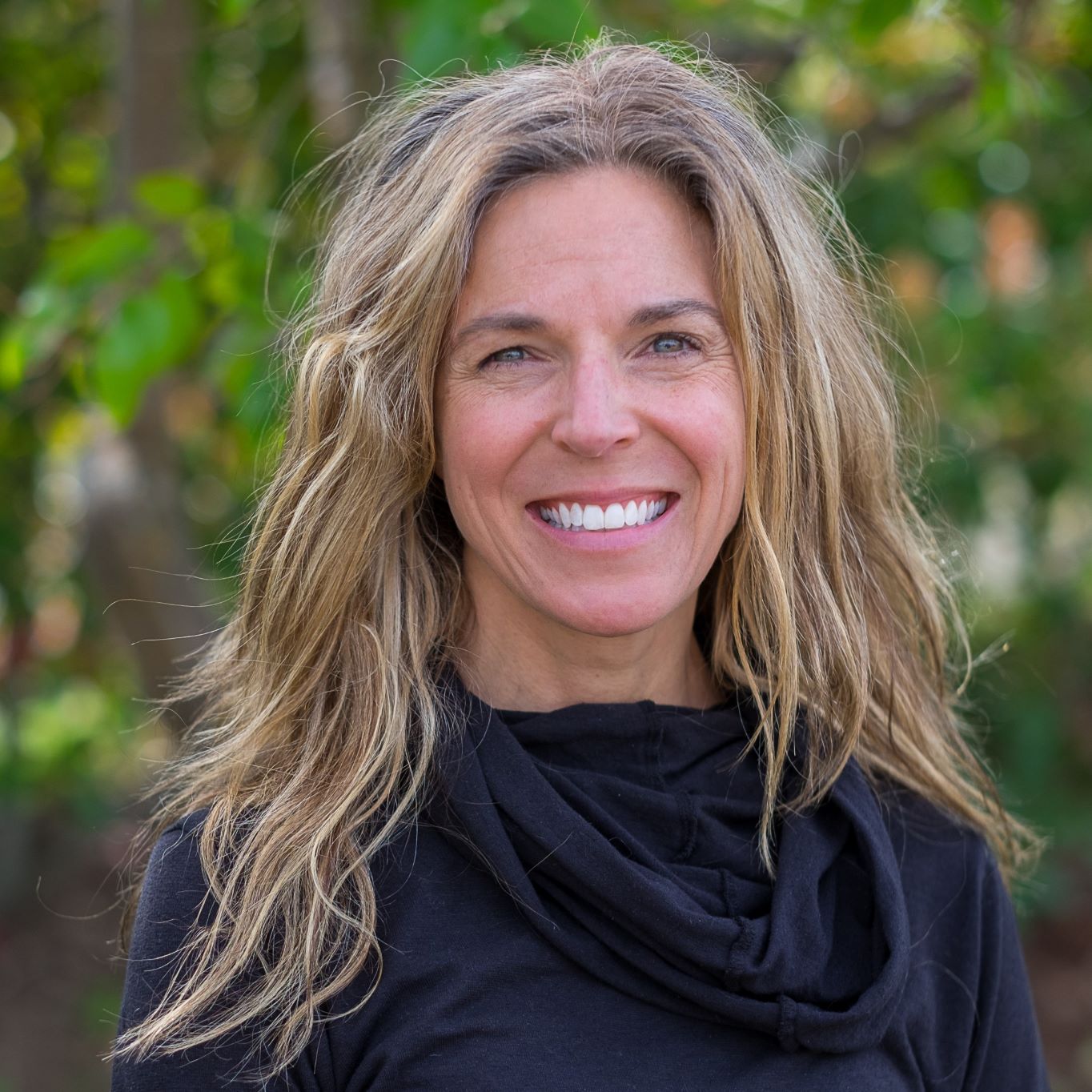 Jennifer Gibbs smiling in front of a leafy background