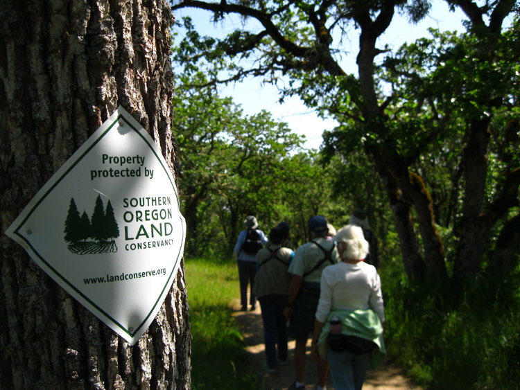 A sign reading "Property protected by Southern Oregon Land Conservancy" on a tree